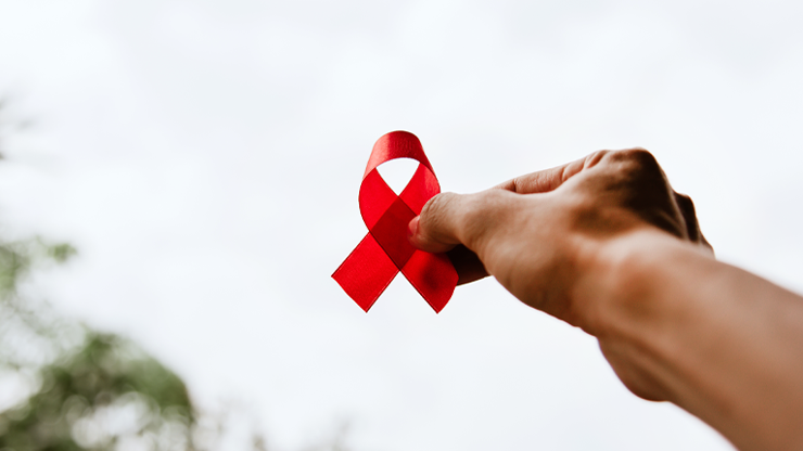 dłoń trzymająca czerwoną wstążeczkę - symbol AIDS