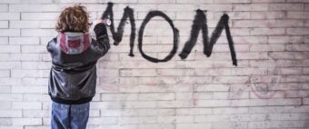 Chłopiec piszący sprayem na murze napis MOM